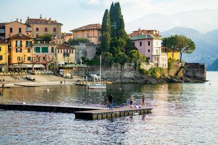 VARENNA, ITALY - APRIL 2022: Tourists and locals spending sunny spring day in Varenna, a town on the shore of Lake Como. Charming location with typical Italian atmosphere. Varenna, Lombardy, Italy.のeditorial素材