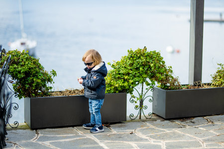 Cute toddler boy having fun exploring on restaurant terrace in Varenna, one of the most picturesque towns on the shore of Lake Como. Varenna, Lombardy, Italy.の写真素材