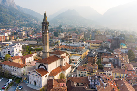 Foggy aerial sunrise cityscape of Lecco town on spring day. Picturesque waterfront of Lecco town located between famous Lake Como and scenic Bergamo Alps mountains. Vacation destination in Italy.の写真素材