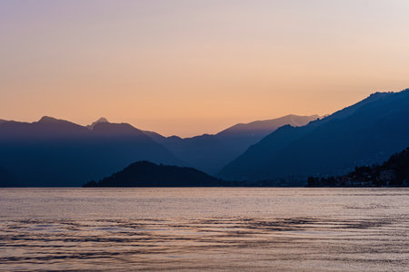 Beautiful aerial view of the famous Como Lake on purple sunset. Clouds reflecting in calm waters of the lake with Alp mountain range on the background. Lombardy, Italy.の写真素材