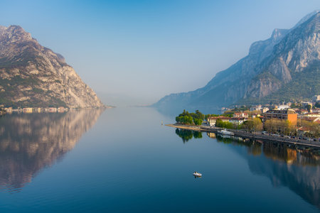 Foggy aerial sunrise cityscape of Lecco town on spring day. Picturesque waterfront of Lecco town located between famous Lake Como and scenic Bergamo Alps mountains. Vacation destination in Italy.の写真素材