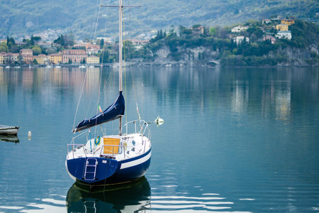 Colourful yacht docked at marina of Lecco town on spring day. Picturesque waterfront of Lecco located between famous Lake Como and scenic Bergamo Alps mountains. Vacation destination in Italy.の写真素材