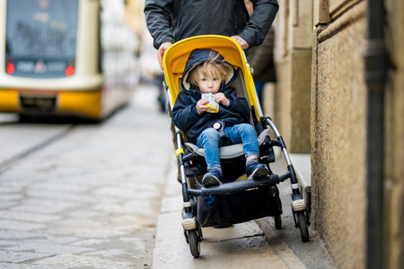 Young father and his toddler son in a stroller walking together down the medieval streets of Milan city. Going on vacation to Europe.の写真素材