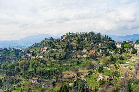 Scenic aerial view of Bergamo city northeast of Milan. Flying over Citta Alta, town's upper district, known by cobblestone streets and encircled by Venetian walls. Bergamo, Lombardy, Italy.の写真素材