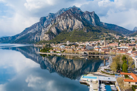 Sunny aerial cityscape of Lecco town on spring day. Picturesque waterfront of Lecco town located between famous Lake Como and scenic Bergamo Alps mountains. Vacation destination in Italy.の写真素材