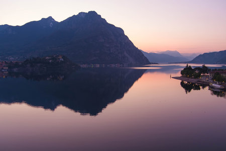 Beautiful aerial view of the famous Como Lake on purple sunset. Mountains reflecting in calm waters of the lake with Alp mountain range on the background. Lombardy, Italy.の写真素材