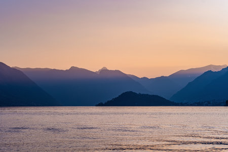 Beautiful aerial view of the famous Como Lake on purple sunset. Clouds reflecting in calm waters of the lake with Alp mountain range on the background. Lombardy, Italy.の写真素材
