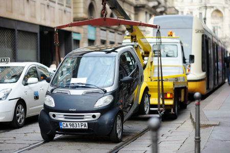 MILAN, ITALY - MAY 2011: Official truck towing away a car that has been parked illegally on street...