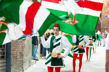 SIENA, ITALY - JULY 2013: Members of the noble Contrada dell'Oca carrying flags with a crowned goose on the Corteo Storico, a historical costume parade in Siena, Tuscany, Italy.のeditorial素材