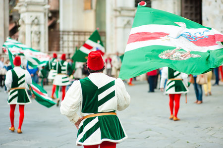 SIENA, ITALY - JULY 2013: Members of the noble Contrada dell'Oca carrying flags with a crowned goose on the Corteo Storico, a historical costume parade in Siena, Tuscany, Italy.のeditorial素材