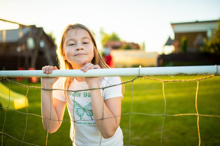 Cute young soccer player having fun playing a soccer game on sunny summer day. Preteen girl playing sports games outdoor. Active leisure.の写真素材