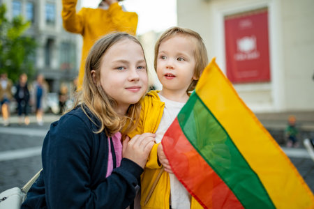 Big sister and a cute toddler boy holding tricolor Lithuanian flag on Lithuanian Statehood Day, Vilnius, Lithuaniaの写真素材