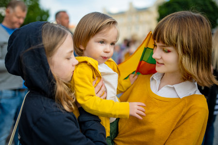 Two big sisters and a cute toddler boy holding tricolor Lithuanian flag on Lithuanian Statehood Day, Vilnius, Lithuaniaの写真素材