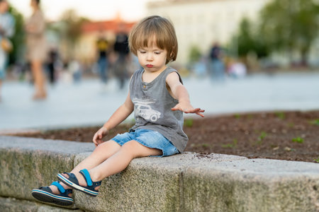 Funny toddler boy having fun in the city on sunny summer day. Outdoor summer activities for small...