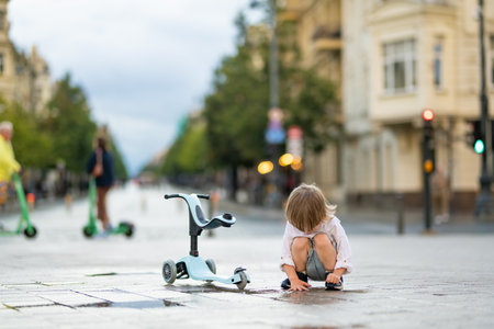 Funny toddler boy riding a baby scooter outdoors on summer day. Kid training balance on mini bike. Summer activities for small kids.の写真素材