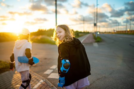 Young girls learning to roller skate on beautiful summer day on a street. Children enjoying roller skating ride outdoors.の写真素材