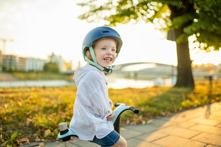 Funny toddler boy riding a baby scooter outdoors on summer day. Kid training balance on bike. Summer activities for small kids.の写真素材