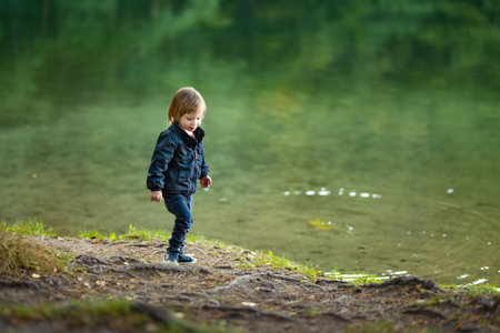 Adorable toddler boy admiring the Balsys lake, one of six Green Lakes, located in Verkiai Regional Park. Child exploring nature on autumn day in Vilnius, Lithuania. Fun autumn activities for kids.の写真素材