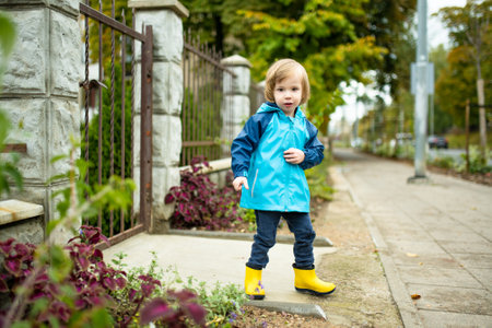 Funny toddler boy having fun outdoors on sunny autumn day. Child exploring nature. Kid playing in a...
