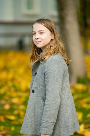 Adorable young girl having fun on beautiful autumn day. Happy teenager portrait in autumn park. Autumn activities for children.の写真素材