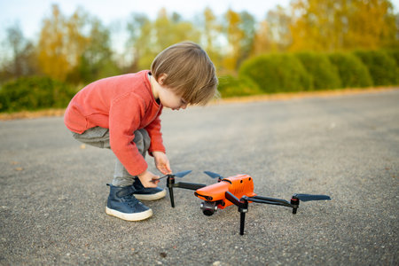 Cute toddler boy watching a drone. Cute toddler boy helping his father to operate a drone by remote control. Family leisure.の写真素材