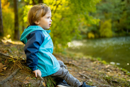 Adorable toddler boy having fun by the Gela lake on sunny fall day. Child exploring nature on autumn day in Vilnius, Lithuania. Fun autumn activities for kids.の写真素材