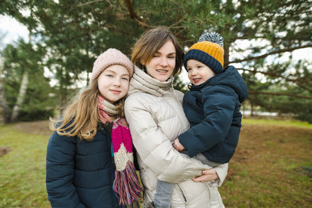 Two big sisters and their toddler brother having fun outdoors. Two young girls holding their sibling...