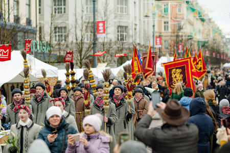 VILNIUS, LITHUANIA - MARCH 4, 2023: Cheerful people participating in humorous parade during Kaziuko muge or Kaziukas, traditional Easter market, crafts fair held every March on Old Town streets.のeditorial素材