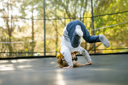 Cute little boy jumping on a trampoline in a backyard on warm and sunny summer day. Sports and...