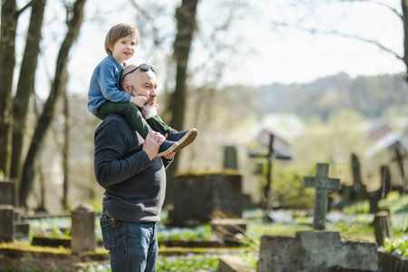 Cute toddler boy and his father admiring blue scilla siberica spring flowers blossoming in April in Bernardine cemetery, one of the three oldest graveyards in Vilnius, Lithuania.の写真素材