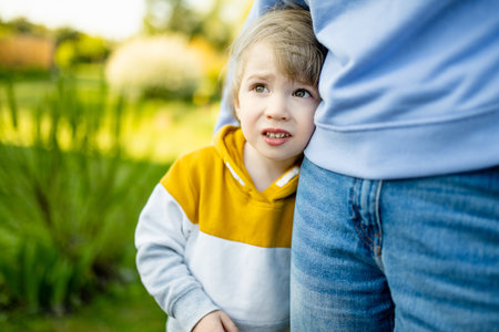 Cute funny toddler boy hugging his mother. Mom and son having fun on sunny summer day in a park. Adorable son being held by his mommy.の写真素材