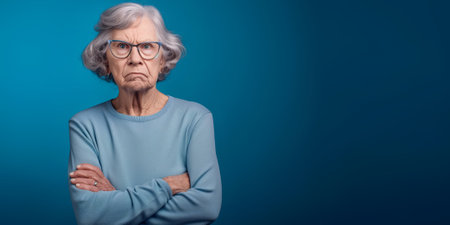 Grumpy senior woman looking at camera with resentment and disapproval, on solid background with copy space. Generative AI.の素材