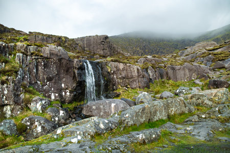 Small waterfall at the Conor Pass, one of the highest Irish mountain passes served by an asphalted road, located on the south-western end of the Dingle Peninsula, County Kerry, Irelandの写真素材