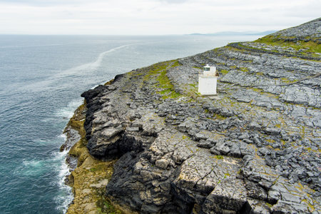Black Head Lighthouse, situated in the rough rocky landscape of Burren, amidst a bizarre scenery of steep limestone mountains and rocky coastline, County Clare, Ireland.の写真素材