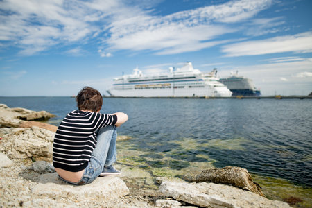 Teenage sister sitting on a rocks watching cruise ships docked in the port of Tallinn.の写真素材