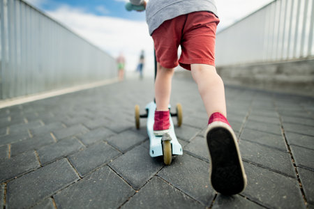Cute little boy riding his kick scooter in the port of Tallinn. Active leisure for small kids.