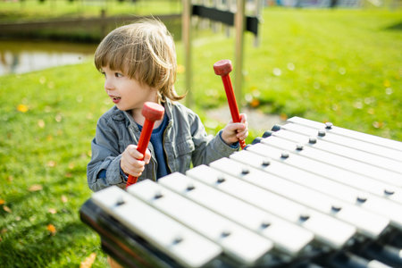 Cute toddler boy having fun on a playground outdoors on warm autumn day. Active leisure for kids in fall.の写真素材