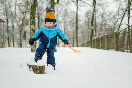 Adorable little boy having fun on snowy winter day. Cute child wearing warm clothes playing in a snow. Winter activities for family with kids.の写真素材