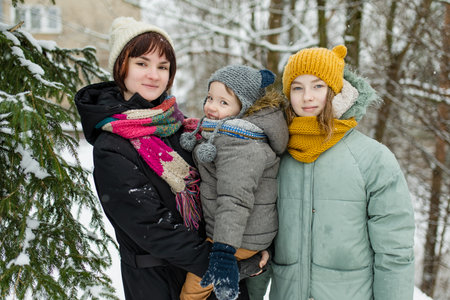 Two big sisters and their toddler brother having fun outdoors. Two young girls holding their sibling...