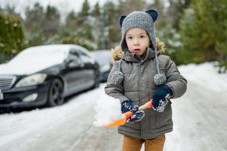 Adorable little boy having fun on snowy winter day. Cute child wearing warm clothes playing in a snow. Winter activities for family with kids.の写真素材