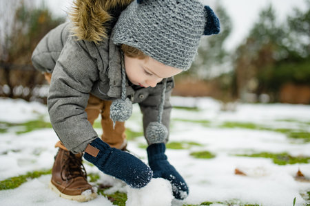 Adorable little boy having fun on snowy winter day. Cute child wearing warm clothes playing in a snow. Winter activities for family with kids.の写真素材