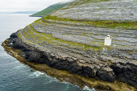 Black Head Lighthouse, situated in the rough rocky landscape of Burren, amidst a bizarre scenery of steep limestone mountains and rocky coastline, County Clare, Ireland.の写真素材