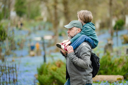 Cute little boy and his father admiring blue scilla siberica spring flowers blossoming in April in Bernardine cemetery, one of the three oldest graveyards in Vilnius, Lithuania.の写真素材