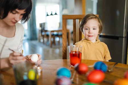 Big sister and her little brother dyeing Easter eggs at home. Children painting colorful eggs for Easter hunt. Kids getting ready for Easter celebration. Family traditions.の写真素材