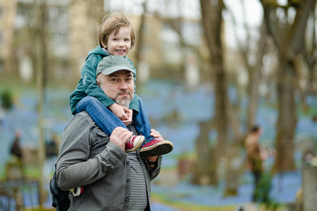 Cute little boy and his father admiring blue scilla siberica spring flowers blossoming in April in Bernardine cemetery, one of the three oldest graveyards in Vilnius, Lithuania.の写真素材