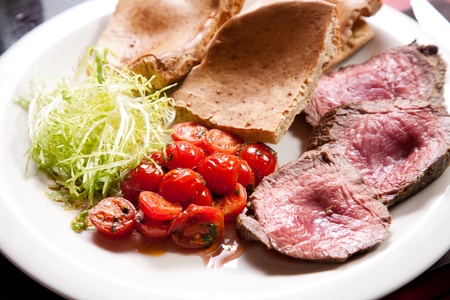 Slices of juicy roast beef with vegetablesの写真素材