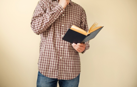 Man in brown plaid shirt reading a bookの写真素材