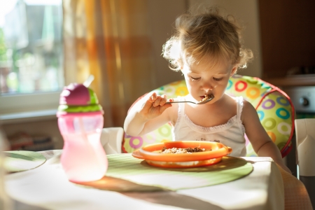 Little baby girl eating breakfast. Beautiful natural light Little baby girl eating breakfast. Beautiful natural light