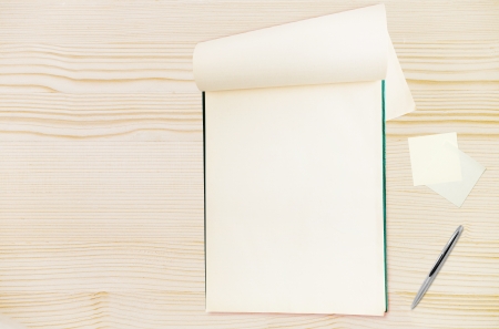 Blank notepad with pen on wood table, free space for textの写真素材
