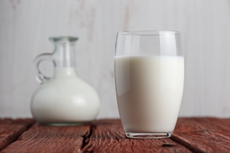 Glass of milk standing on old wooden table の写真素材